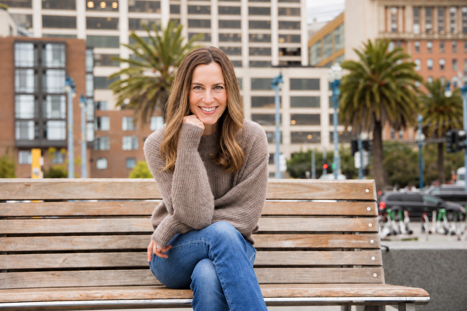 Sarah Boutin smiling, seated on a wooden bench in San Francisco